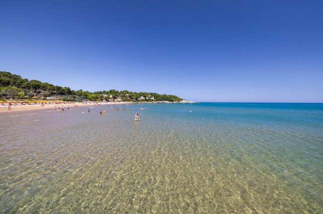 Mare limpido con bagnanti e cielo sereno.