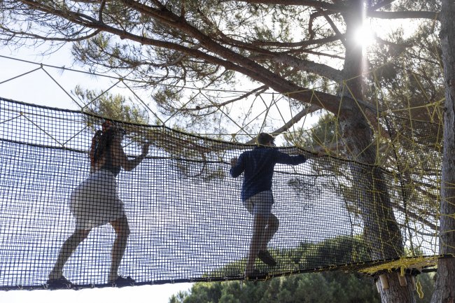 Persone camminano su una rete tra gli alberi.