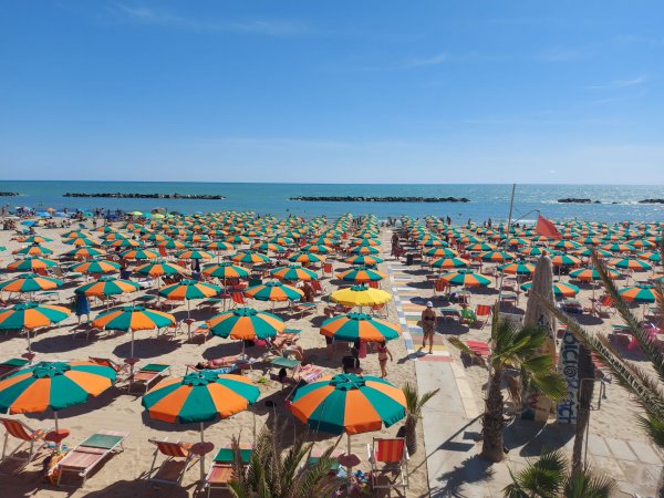 Spiaggia con molti ombrelloni colorati.