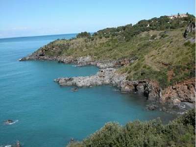 Una costa rocciosa con mare blu e vegetazione verde sulle scogliere.
