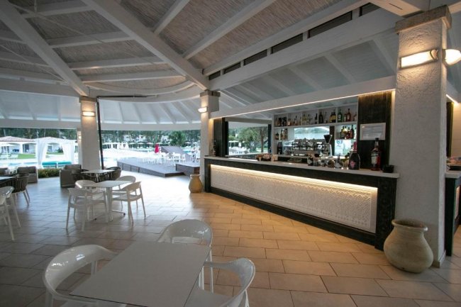 Bar moderno con sedie bianche e vista sulla piscina.