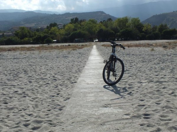 Bicicletta parcheggiata su un sentiero in una spiaggia sabbiosa.
