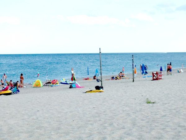 Spiaggia sabbiosa con bagnanti e ombrelloni colorati.