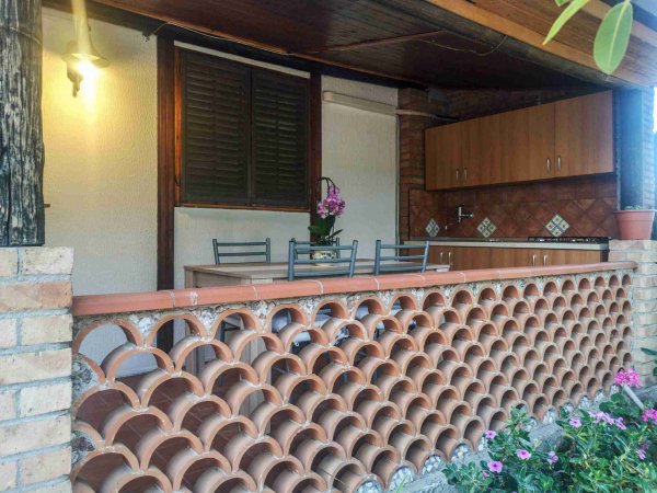 Cucina all'aperto con tavolo e sedie.