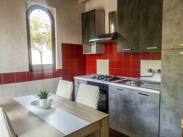 Cucina moderna con pareti rosse e tavolo con sedie bianche.
