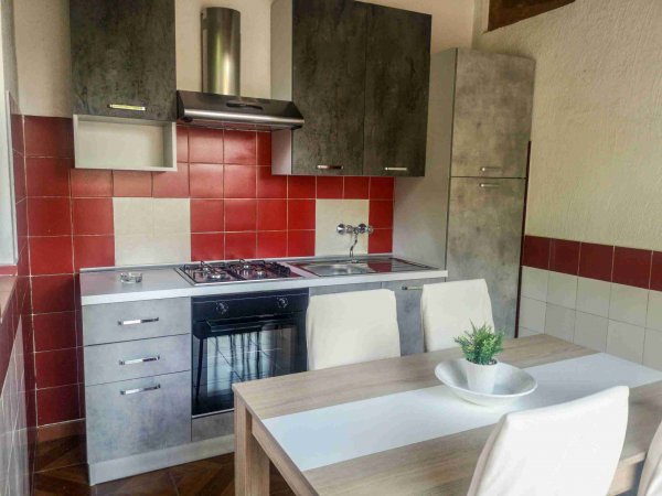 Cucina con forno, fornelli, tavolo e sedie.