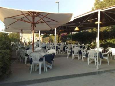 Area all'aperto con sedie bianche e ombrelloni in un ristorante.