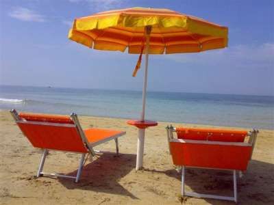 Due lettini arancioni e un ombrellone sulla spiaggia.