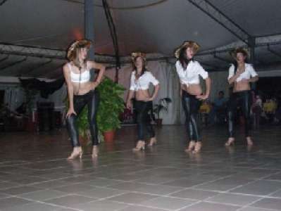 Quattro donne in abito da cowgirl ballano su un palco coperto.