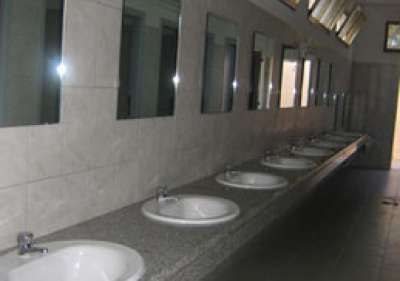 Un bagno pubblico con una lunga fila di lavandini e specchi.