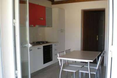 Cucina moderna con tavolo, sedie e mobile rosso sopra i fornelli.
