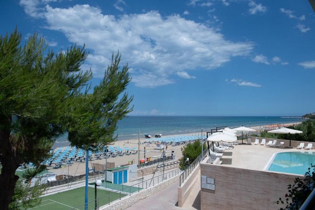Piscina e spiaggia con ombrelloni blu.