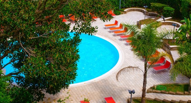 Piscina circolare con lettini arancioni.