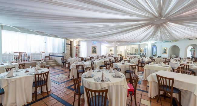 Sala da pranzo elegante con tavoli rotondi apparecchiati.