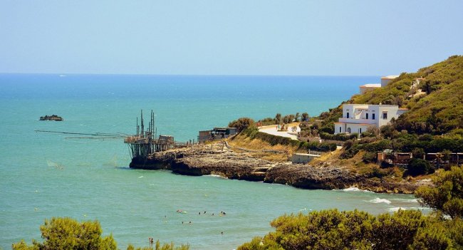 Costa rocciosa con mare blu e costruzione.