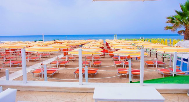 Spiaggia con ombrelloni e lettini arancioni.