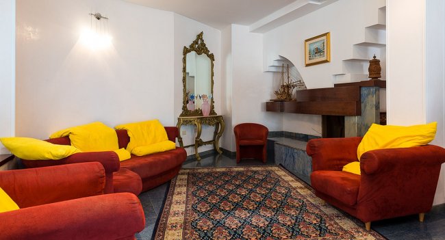 Sala con poltrone rosse e specchio.