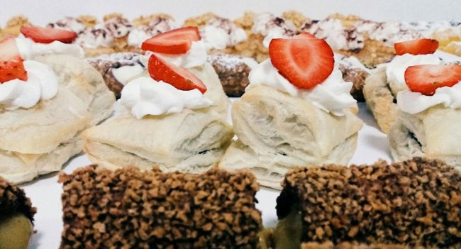 Sfogliatine con panna e fragole su un vassoio.