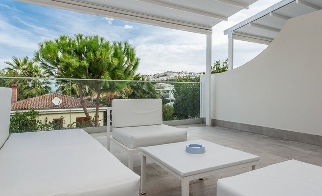 Terrazza moderna con divani bianchi e piante.