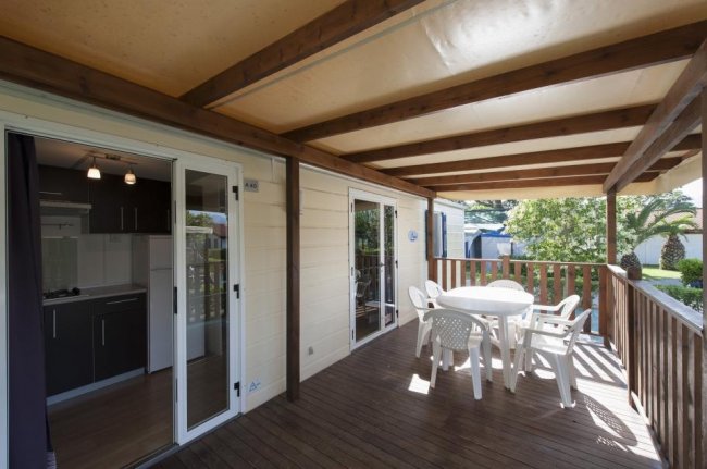 Veranda in legno con tavolo e sedie bianche.