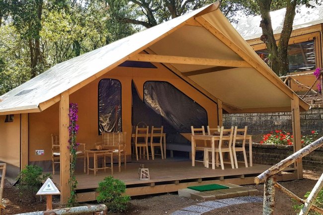 Tenda da campeggio con veranda e sedie in legno.