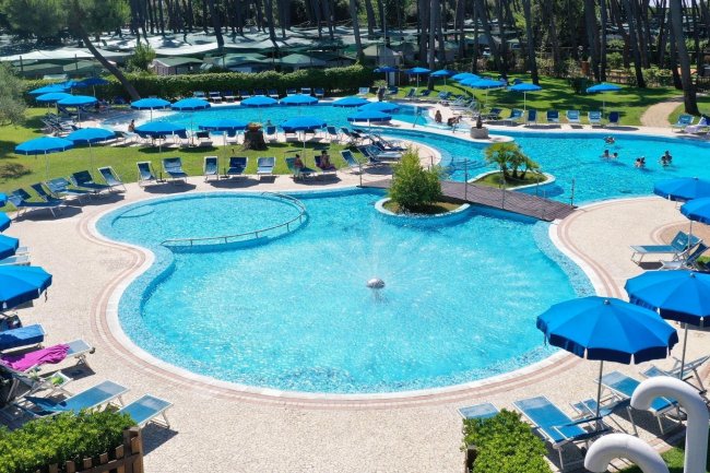 Piscina con sedie a sdraio e ombrelloni blu.