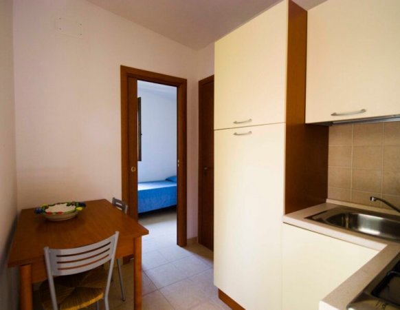 Cucina con tavolo e vista su camera da letto.