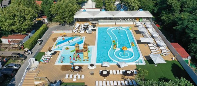 Piscina con giochi d'acqua e lettini bianchi.