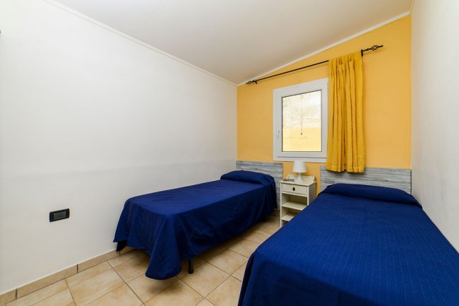 Camera con due letti singoli e parete gialla.