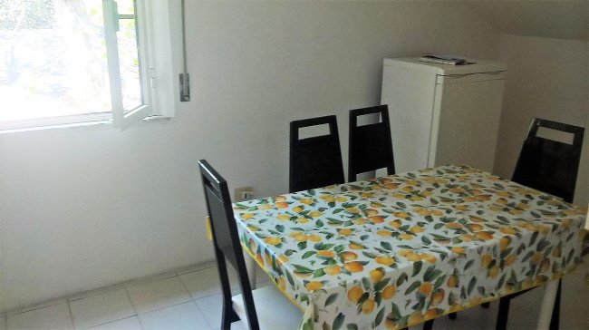 Tavolo con tovaglia a limoni e quattro sedie in cucina luminosa.