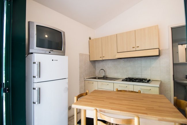 Cucina con tavolo, frigorifero e TV.