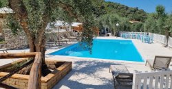 Una baia rocciosa con acque turchesi, una barca ormeggiata e persone sulla spiaggia.