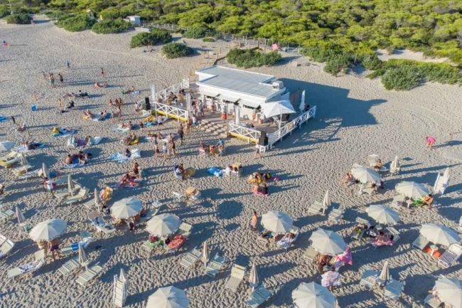 Spiaggia affollata con ombrelloni e chiosco.