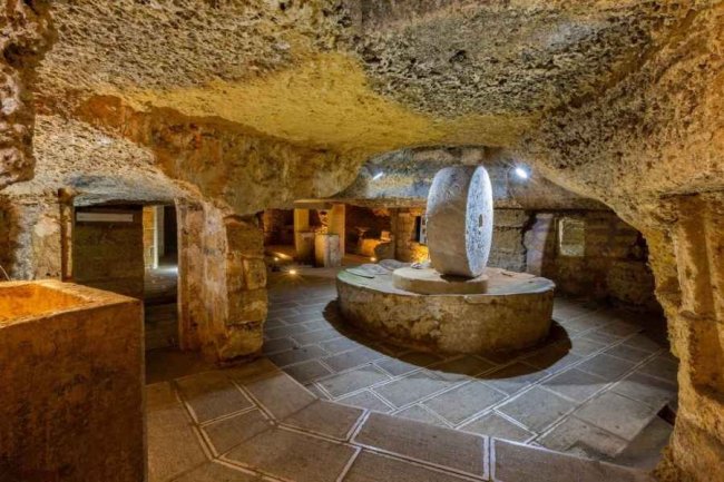 Antica sala sotterranea con macina in pietra.