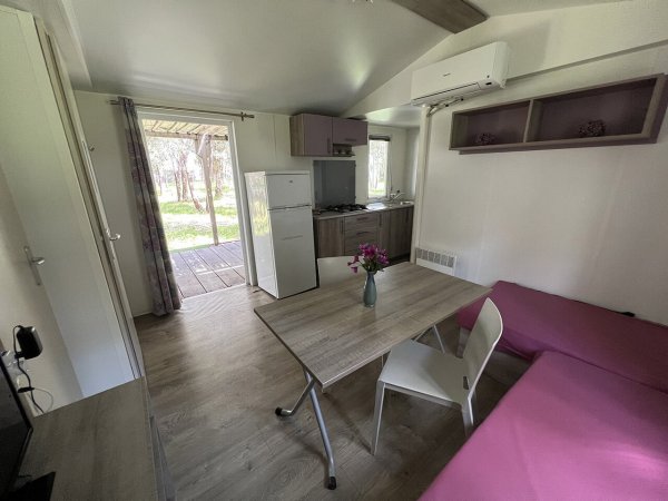 Interno di una casa mobile con tavolo, sedie e divano rosa.