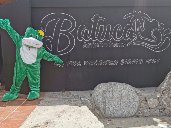 Costume da rana verde davanti a un cartello con la scritta 