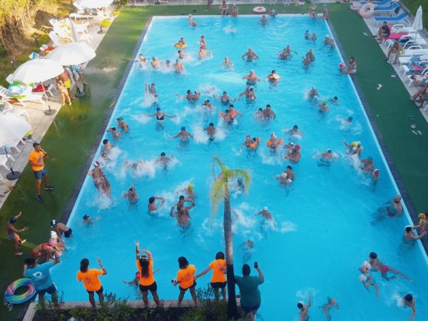 Persone che nuotano e si divertono in una grande piscina all'aperto.