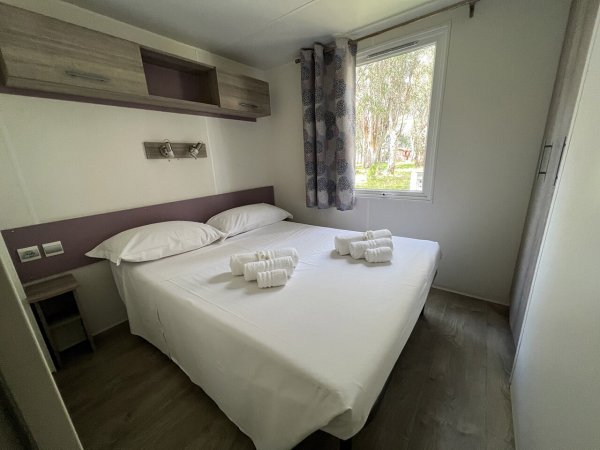 Camera da letto con letto matrimoniale, asciugamani piegati e finestra.