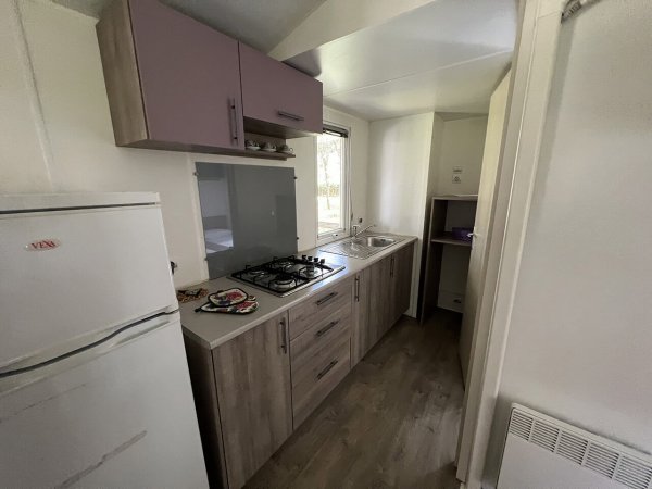 Cucina moderna in legno chiaro con frigorifero, piano cottura e lavello.
