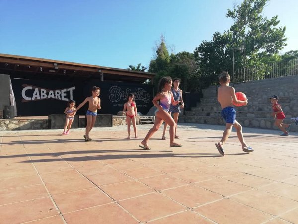 Bambini che giocano a palla in uno spazio all'aperto con scritto 