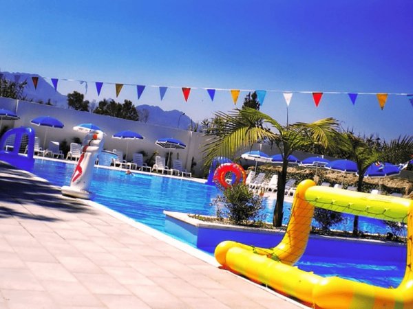 Piscina con decorazioni colorate e sdraio blu sotto un cielo sereno.