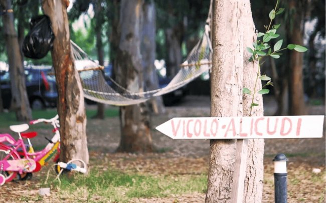 Parco con un'amaca, bici per bambini e un cartello che indica 