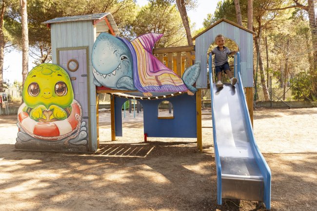Un bambino scivola da uno scivolo vicino a una struttura di gioco.