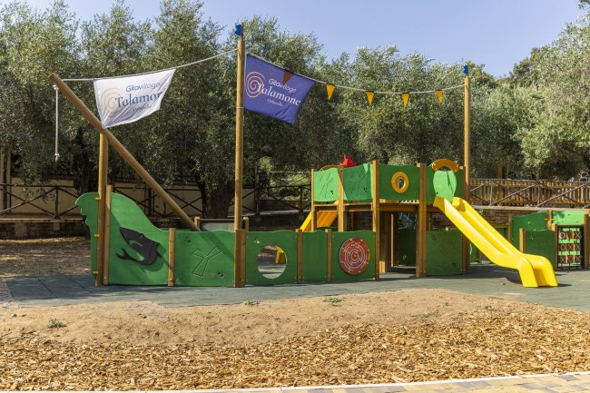 Parco giochi per bambini con scivolo e strutture verdi.