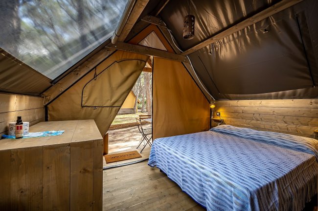 Tenda con letto matrimoniale e scrivania.