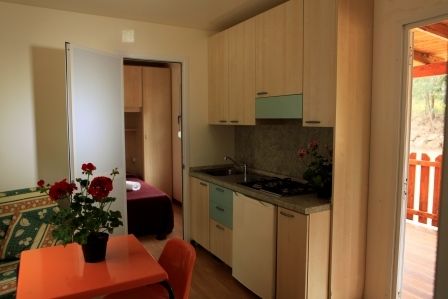 Interno cucina con tavolo arancione e fiori.