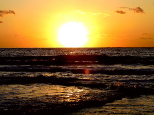 Sole al tramonto sopra il mare con onde leggere.