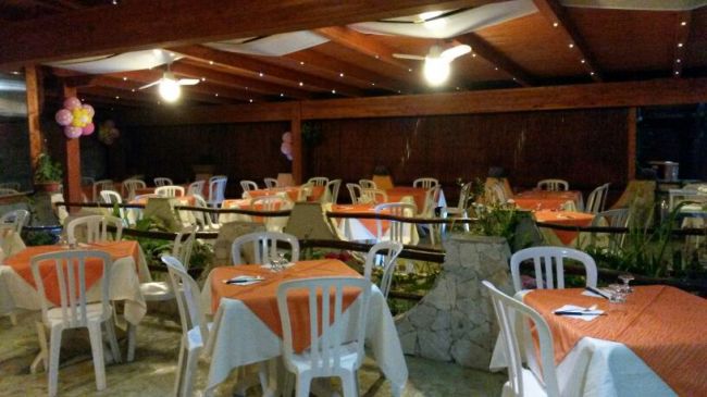Sala da pranzo con tavoli apparecchiati e sedie bianche.