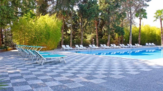 Piscina con sdraio e pavimento a scacchi.