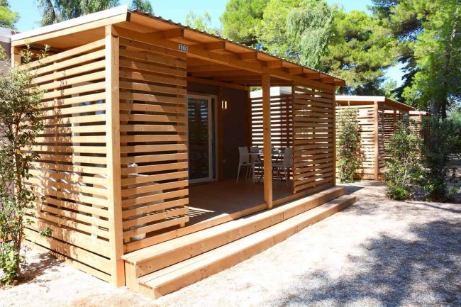 Bungalow in legno con terrazza e sedie.